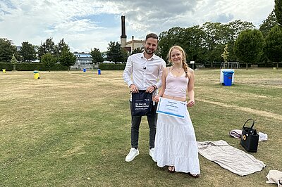 Ein Mann und eine Frau stehen auf einer kurz gemähten Liegewiese im Freibad.