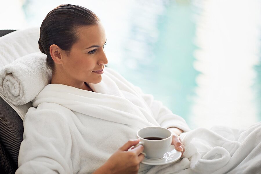 Frau entspannt sich in einer Liege am Schwimmbad