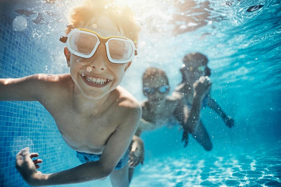 Kinder schwimmen unter Wasser und freuen sich