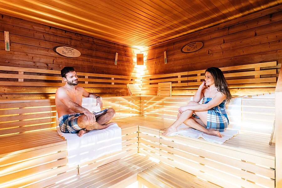 Eine Frau und ein Mann sitzen in einer Sauna